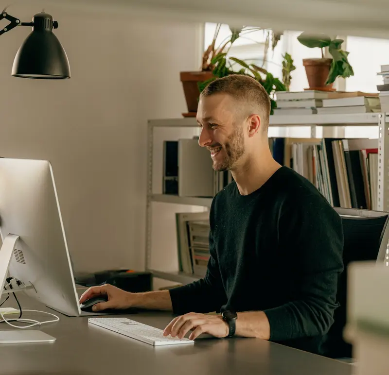 Lachende medewerker aan het werk achter de computer